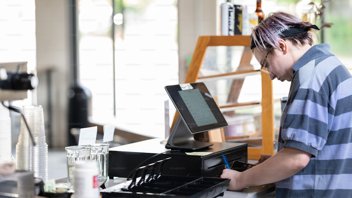 Hombre trabajando detrás del mostrador de un café con sistema de punto de venta